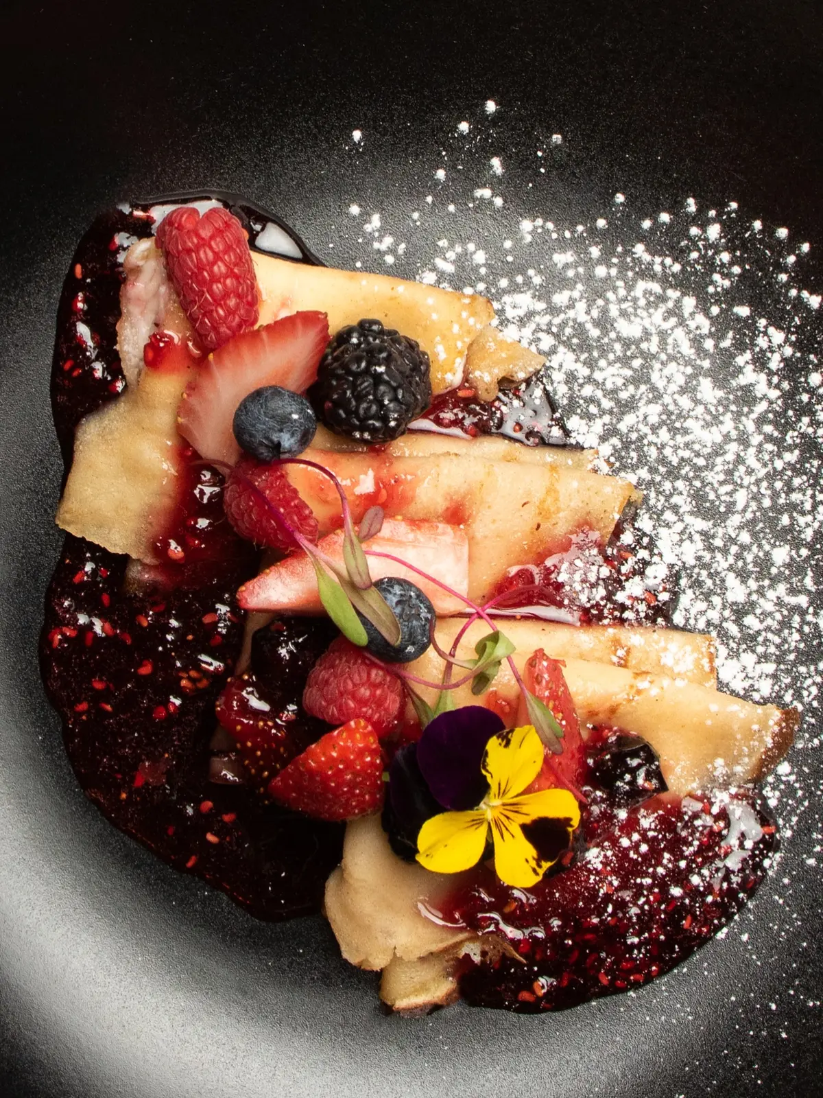 Crepas con frutos del bosque, flores y azúcar glas
