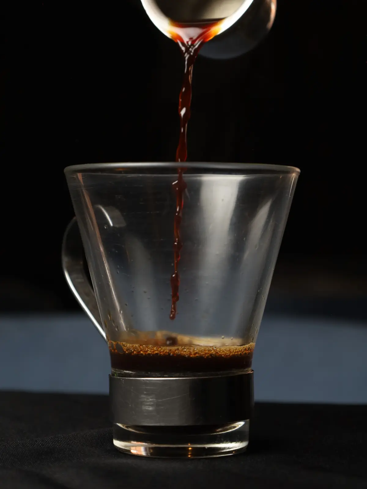 Café cayendo en una taza de vidrio